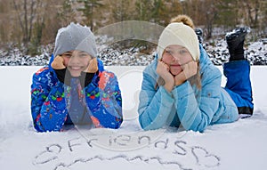 Happy teens luing in the snow. Inscription friends