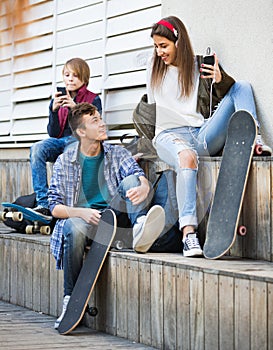 Happy teens playing on smarthphones and listening to music