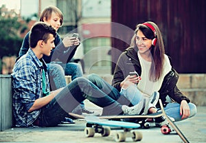 Happy teens playing on smarthphones and listening to music