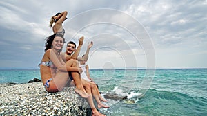 Happy teens sitting on beach pier having fun blowing kisses and waving hands