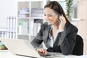 Happy telemarketer with laptop attending call at office photo