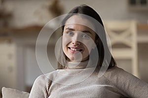 Happy tenant girl resting on home sofa, looking at camera