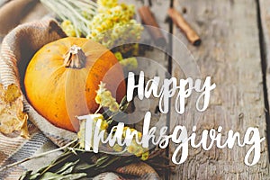 Happy Thanksgiving Card. Happy thanksgiving text on pumpkin, autumn flowers, herbs, cozy blanket on rustic old wood. Season`s