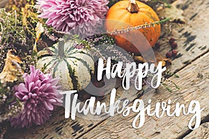 Happy Thanksgiving Card. Happy thanksgiving text on pumpkins, dahlias flowers, heather on rustic old wood. Season`s greetings,