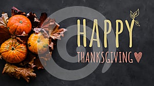 Happy thanksgiving day background. Pumpkins and autumn leaves on dark backdrop.