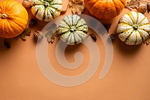 Happy Thanksgiving day postcard design. Flat lay composition with pumpkins, dry leaves, acorns, walnuts on orange background.