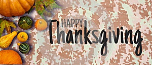 Happy Thanksgiving flat lay with colorful pumpkins and fruits on army digital pattern textile photo