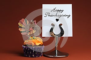 Happy Thanksgiving message with orange cupcake with turkey decoration.
