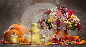 happy thanksgiving still life. autumn flowers roses, chrysanthemums, asters in a pumpkin vase with candle and lantern