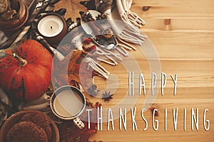 Happy Thanksgiving text on autumn flat lay with pumpkin,coffee,candle,fall leaves, cookies,berries,nuts,acorns on rustic blanket