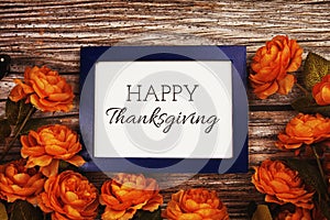 Happy Thanksgiving text in blue border frame with flower decoration on wooden background