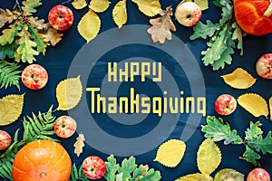 Happy Thanksgiving text with pumpkins and leaves over dark wood background