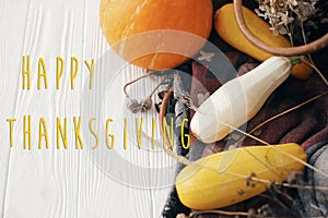 Happy Thanksgiving text, seasons greeting card. Thanksgiving sign. Pumpkin ,zucchini , wicker basket on white wooden background.