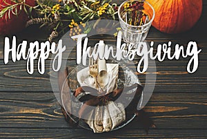Happy Thanksgiving text sign on cutlery, linen, anise star, plate, autumnal floral arrangement and pumpkin on rustic wood. Seasons