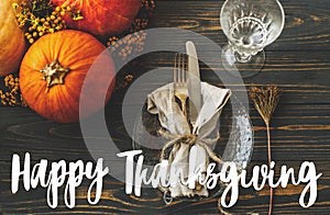 Happy Thanksgiving text sign on eco friendly thanksgiving dinner table setting. Stylish plate, linen, pumpkin, autumn flowers on