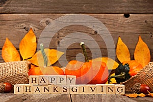 Happy Thanksgiving wooden blocks with wood background,pumpkins, leaves