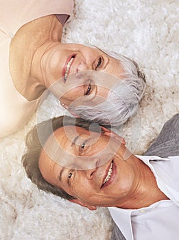 Happy in their golden years. High angle shot of a happy senior couple lying down on the carpet.