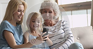 Happy three age intergenerational women family having fun with cellphone