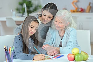 happy three-generation family cooking vegetable salad together in kitchen