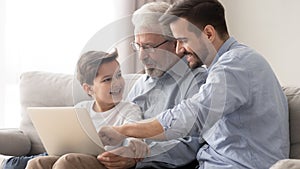 Happy three generation family grandfather father and grandson using laptop