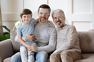 Happy three generations male family resting on couch.