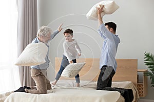 Happy three generations men family having pillow fight on bed