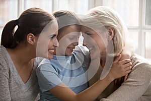 Happy three generations of women cuddle at home