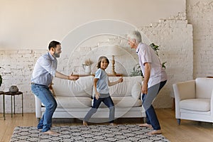 Happy three male generations family dancing at home.