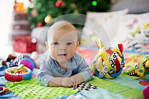 Happy three months old baby boy, playing at home on a colorful a