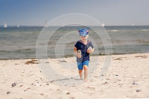 Happy three-year-old child is going  on the sea beach and holding stones in hands