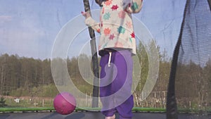 Happy three year old girl jumping on a trampoline. Emotional joyful portrait. Slow motion