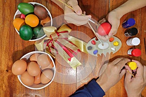 Happy time of family members are painting colorful eggs with a paintbrush and palette for preparing happy Easter day.