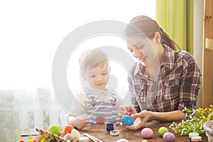 Happy time while painting easter eggs. Easter concept. Happy mother and her cute child getting ready for Easter by