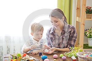 Happy time while painting easter eggs. Easter concept. Happy mother and her cute child getting ready for Easter by