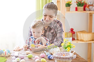 Happy time while painting easter eggs. Easter concept. Happy mother and her cute child getting ready for Easter by