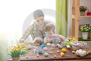 Happy time while painting easter eggs. Easter concept. Happy mother and her cute child getting ready for Easter by