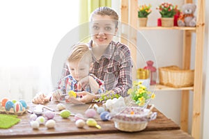 Happy time while painting easter eggs. Easter concept. Happy mother and her cute child getting ready for Easter by