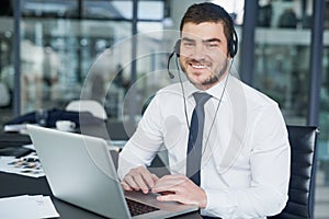 Happy to be or assistance. Portrait of a young customer service representative wearing a headset while sitting at his