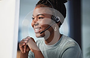 Happy to help. an attractive young customer service agent sitting alone in the office and wearing a headset.