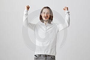 Happy to see score of his team. Indoor shot of loyal fan with long hair and beard raising clenched fists in victory