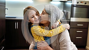 Happy to see you. Portrait of happy grandmother embracing and kissing her cute little preschool granddaughter, standing