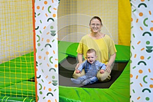 Happy toddler baby boy jumps on a trampoline with his mother in the p
