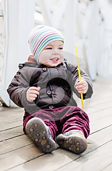 Happy toddler baby boy sitting by the fence