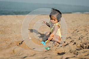 happy toddler baby girl playing sand toy on sea beach