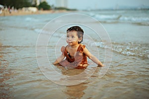 happy toddler baby girl playing sand and water on sea beach