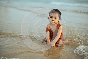 happy toddler baby girl playing sand and water on sea beach