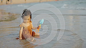 happy toddler baby girl playing toy and water on sea beach