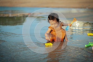 happy toddler baby girl playing toy and water on sea beach