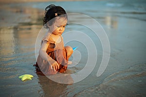 happy toddler baby girl playing toy and water on sea beach