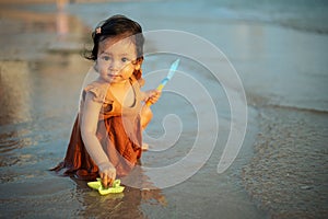 happy toddler baby girl playing toy and water on sea beach